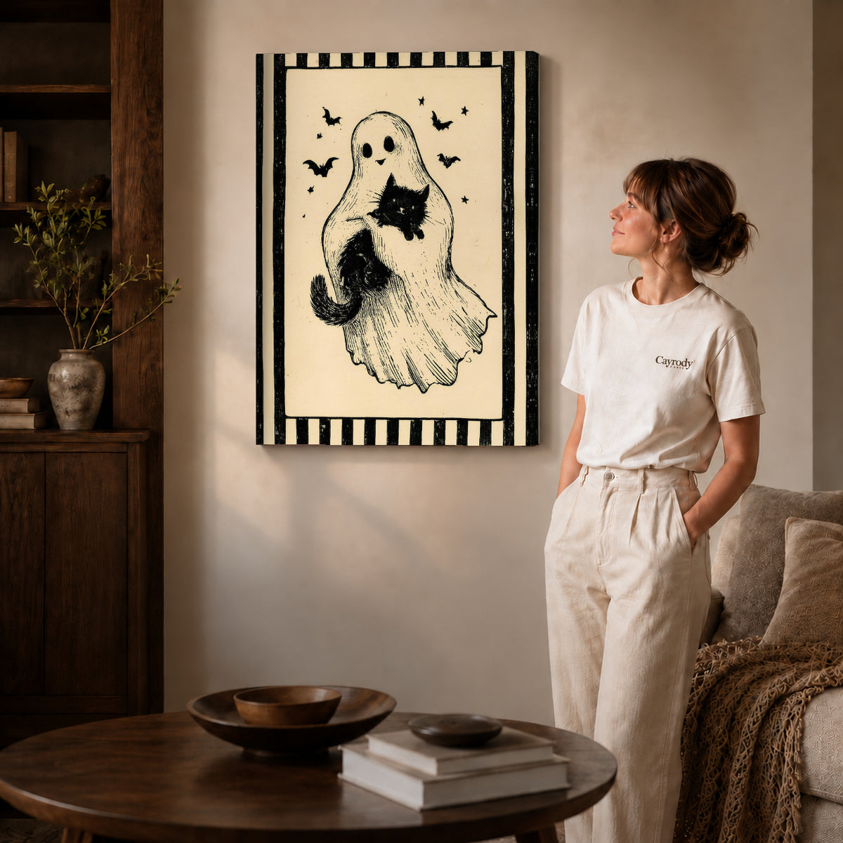 Gallery wrapped ghost and cat canvas art with visible canvas edges beside a standing woman.