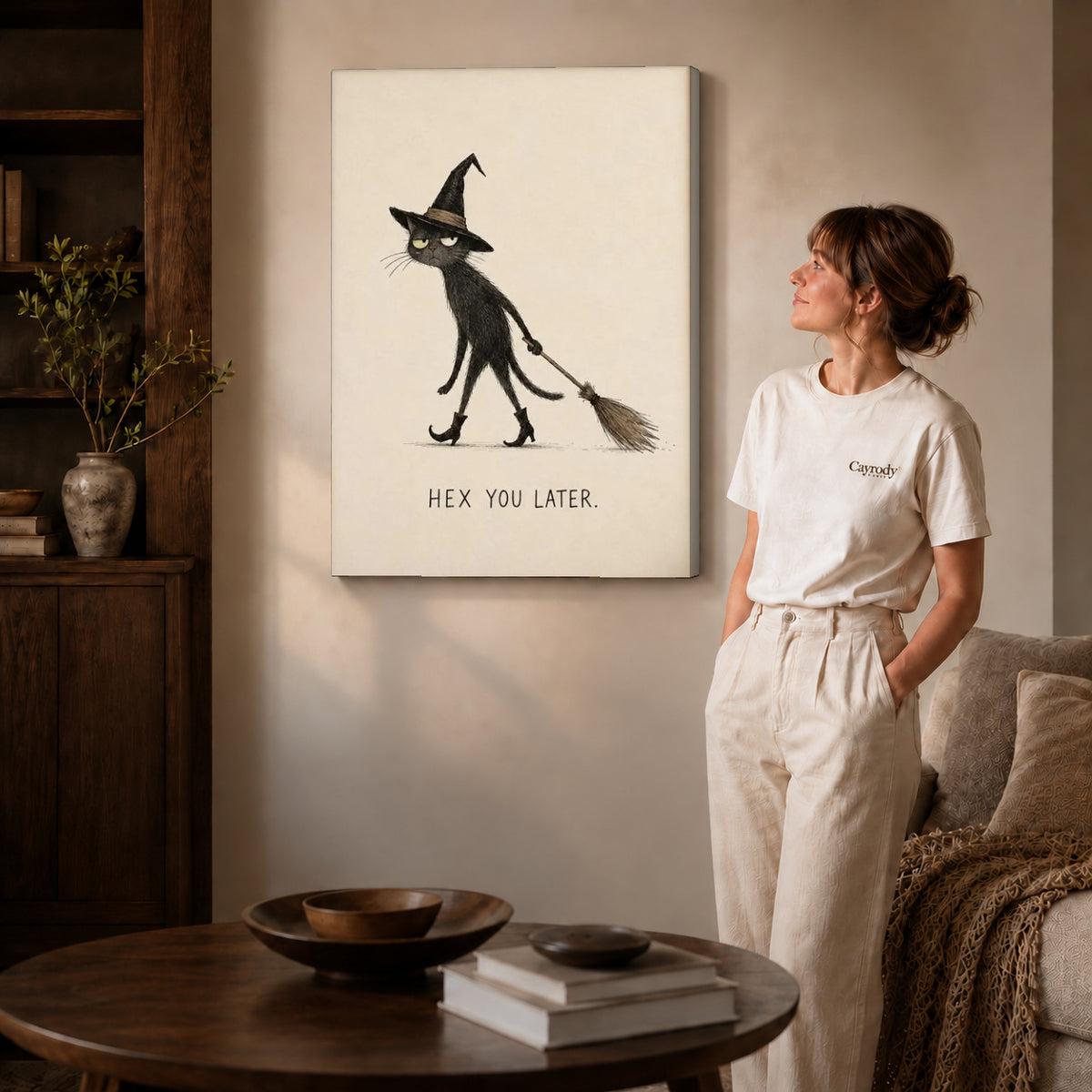 Gallery wrapped broomstick cat canvas art with visible canvas edges beside a standing woman.
