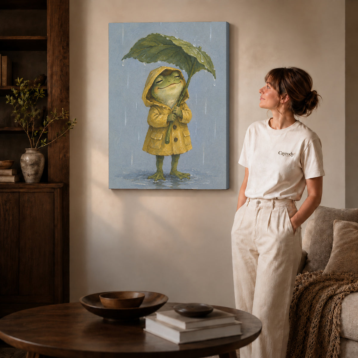 Gallery wrapped raincoat frog canvas art with visible canvas edges beside a standing woman.