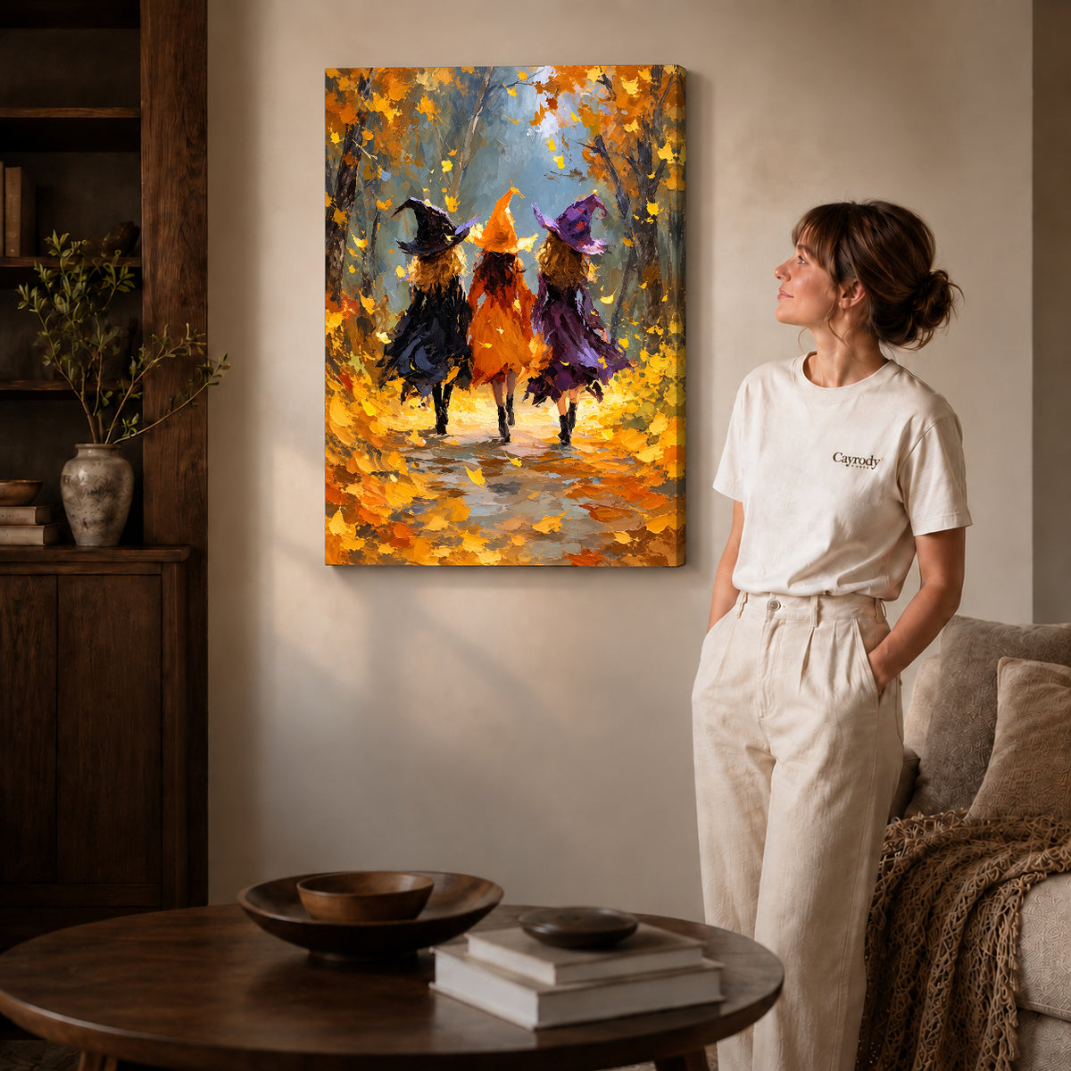 Gallery wrapped autumn witch friends canvas art with visible canvas edges beside a standing woman.