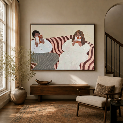 Two women reading figurative canvas wall art in dark walnut float frame above console in bright entryway