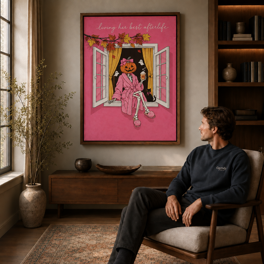 Whimsical Halloween pumpkin skeleton wall art in a black framed canvas over a mid-century armchair in a living room.