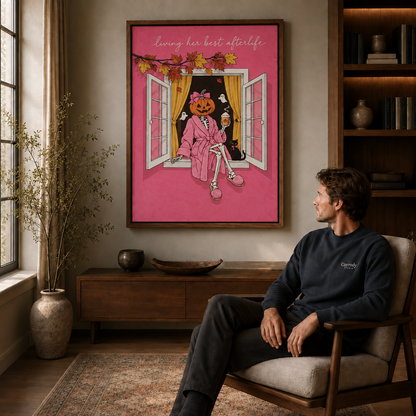 Whimsical Halloween pumpkin skeleton wall art in a black framed canvas over a mid-century armchair in a living room.
