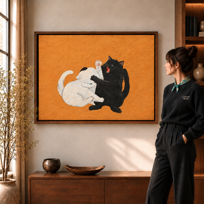 Play-fighting cats canvas art on a textured orange background beside a woman in a warm living room.