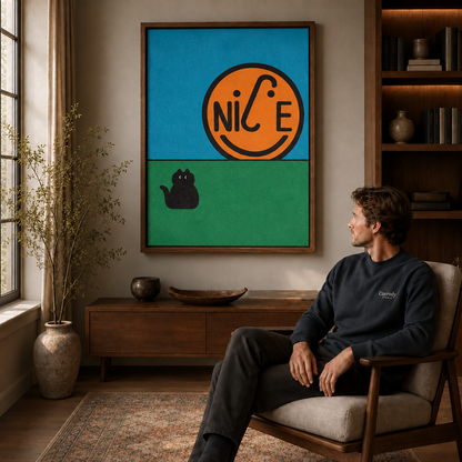 Man seated in an armchair beside a walnut floating-frame wall art of an orange NICE smiley and black cat.