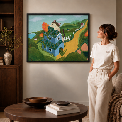 Woman in a cream tee pausing beside the cat house wall art in a slim black frame with soft daylight