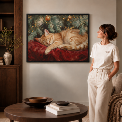 Sleeping orange cat Christmas canvas wall art in a thin black frame beside a woman in white.