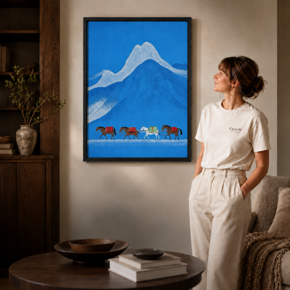 Black-framed minimalist blue landscape art of four pack horses displayed in a neutral living room.