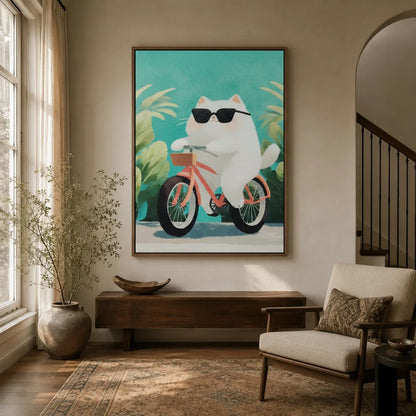Framed canvas of a chubby white cat in sunglasses riding a pink bicycle, displayed in a bright entryway