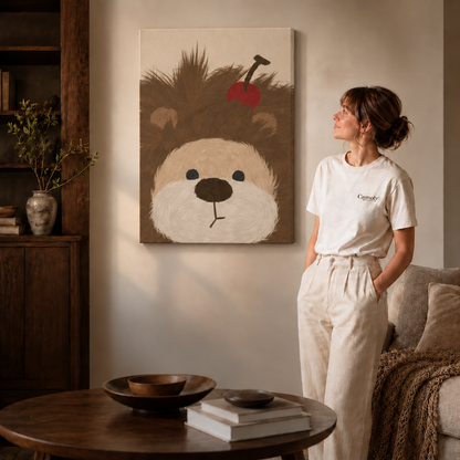 Woman in a cream tee standing next to a gallery-wrapped canvas showing whimsical fluffy brown dog with a red apple.
