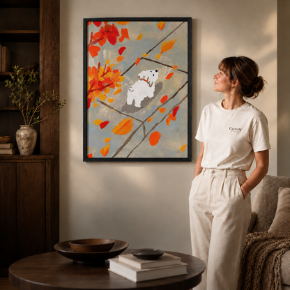 Woman standing near a black framed autumn puppy wall art with falling leaves, warm minimalist interior with soft natural light.