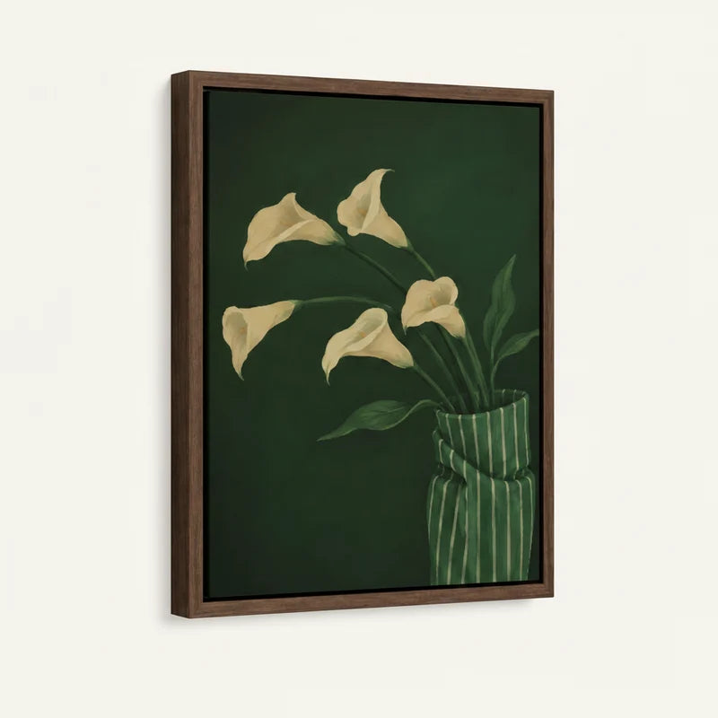 Angled product view of framed canvas — cream calla lilies in striped vase with deep green background in walnut float frame