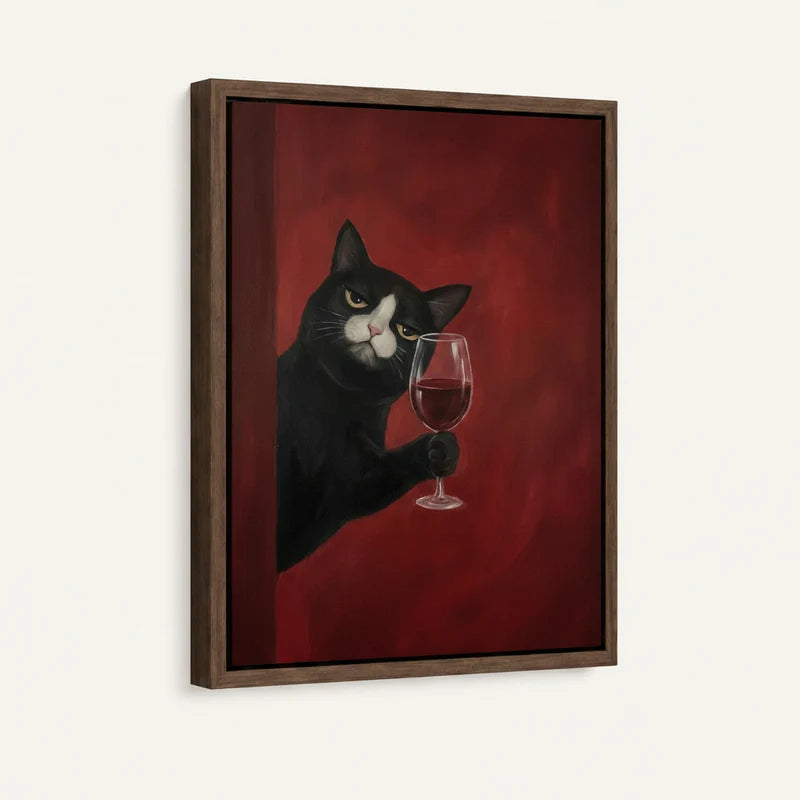 Angled product view of framed canvas — tuxedo cat extending paw with red wine glass on deep crimson in walnut float frame