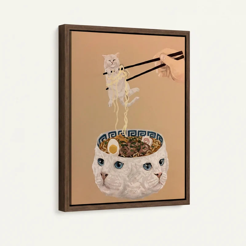 Framed canvas art of a white cat ramen bowl with chopsticks lifting a tiny fluffy cat, warm caramel background