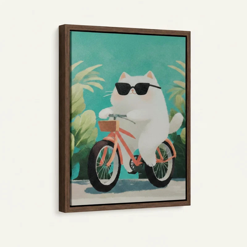 Side-angle view of framed canvas showing cool white cat on pink bike with teal tropical background