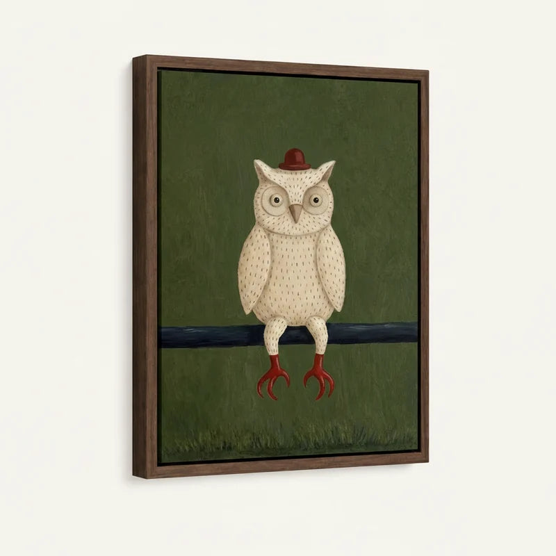 Side-angle view of framed folk art white owl canvas with forest green background and red hat
