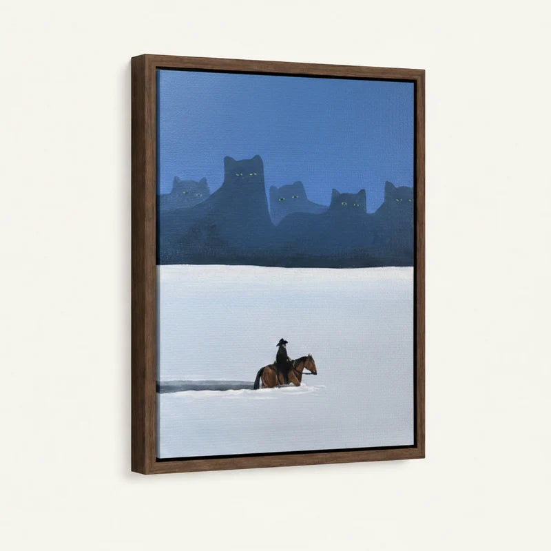 Side-angle view of dark wood floater frame showing lone horseman crossing snowy plain with glowing cat silhouettes at dusk