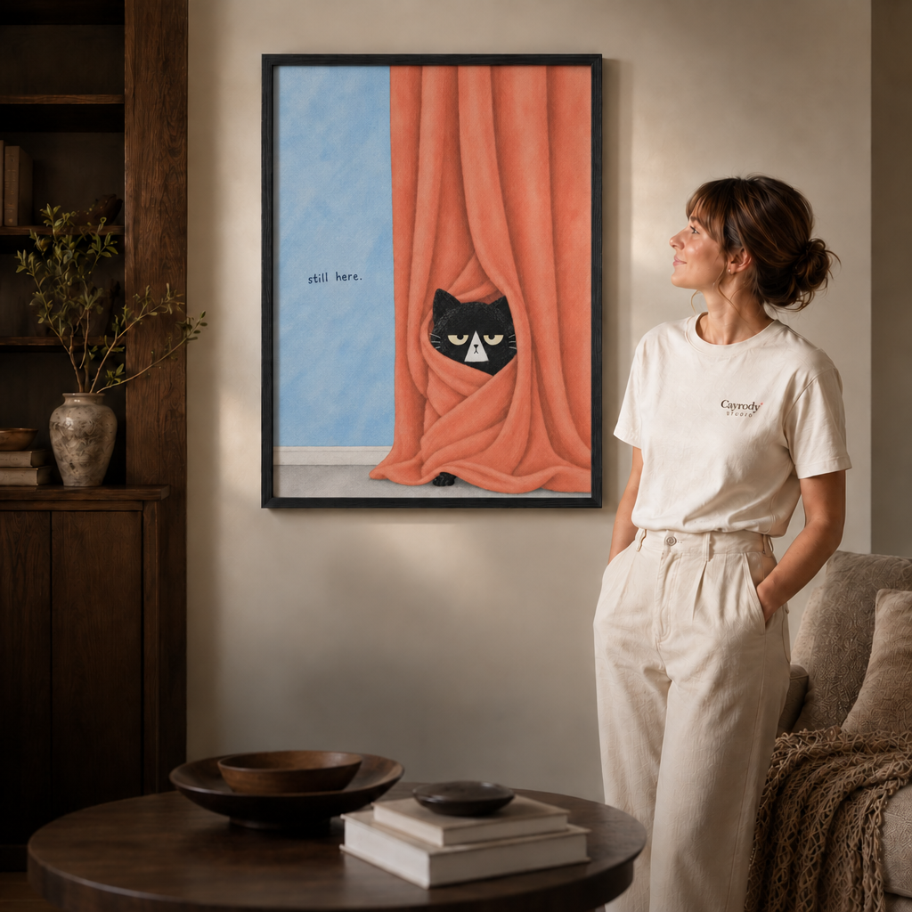 Woman admiring a thin black framed black cat still here artwork in a cozy modern living room.