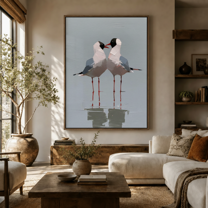 Large coastal seagull couple canvas art in dark frame above sideboard in organic modern living room with olive tree and white sofa