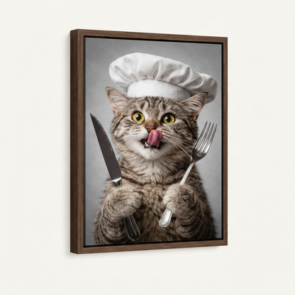 Framed canvas front view of wide-eyed tabby chef cat licking lips with cutlery, gray background