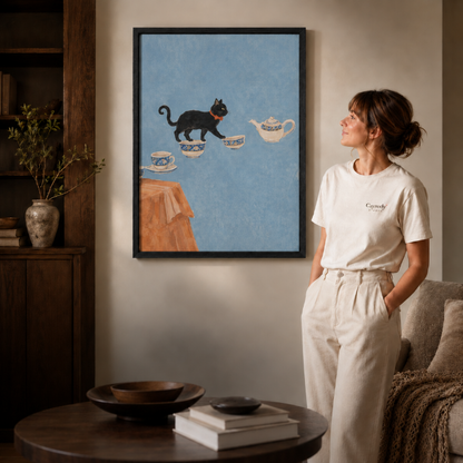 Framed black cat and teacups canvas wall art beside a woman in a warm cream-toned room
