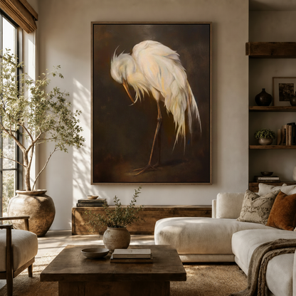Moody egret canvas wall art hung above white sofa in sunlit organic modern living room with olive tree