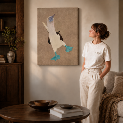 Gallery-wrapped blue-footed booby canvas wall art hanging frameless on a beige wall beside a round coffee table.