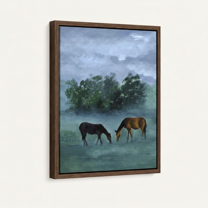 Walnut framed canvas side angle showing black and chestnut horses grazing in blue-green misty meadow with tree backdrop
