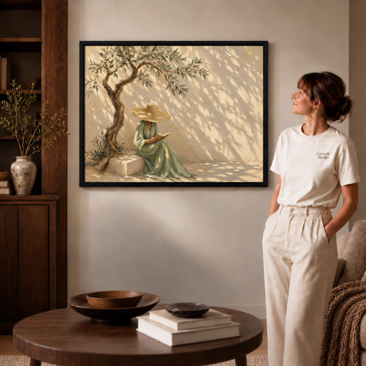 Olive tree reader canvas wall art black framed option shown beside a woman in the softly lit living room.