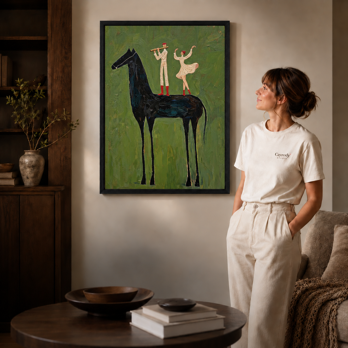 Whimsical black horse canvas wall art in a black frame beside a woman and warm wooden living room furniture.