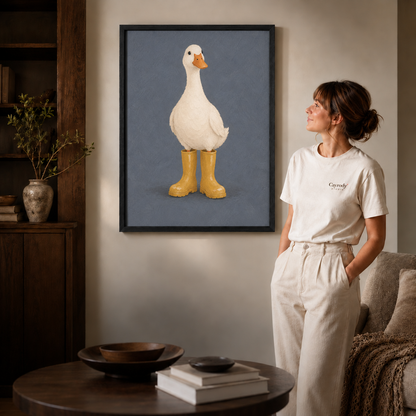 Duck in rain boots wall art in a black frame above a round coffee table and modern sofa