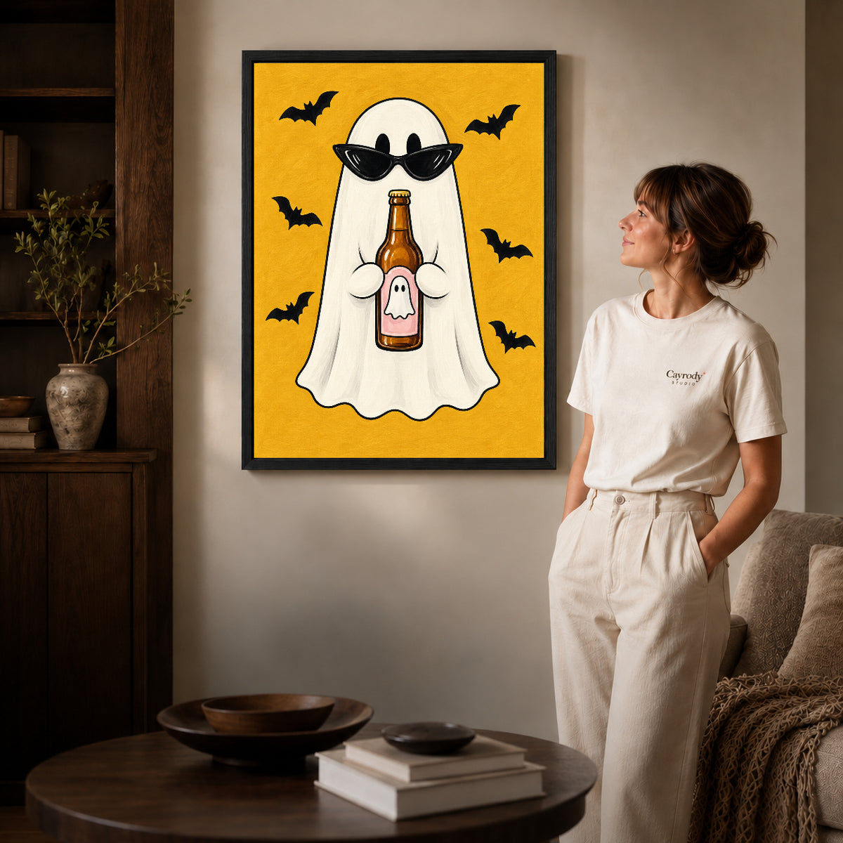 Party Ghost canvas art in a black frame above books in a welcoming living room.