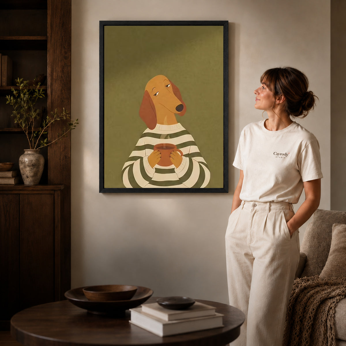 Coffee dog canvas art displayed in a black frame beside a woman, with soft room lighting.