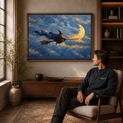 Moonlit witch canvas art above a wooden console near a seated man and leafy branches.