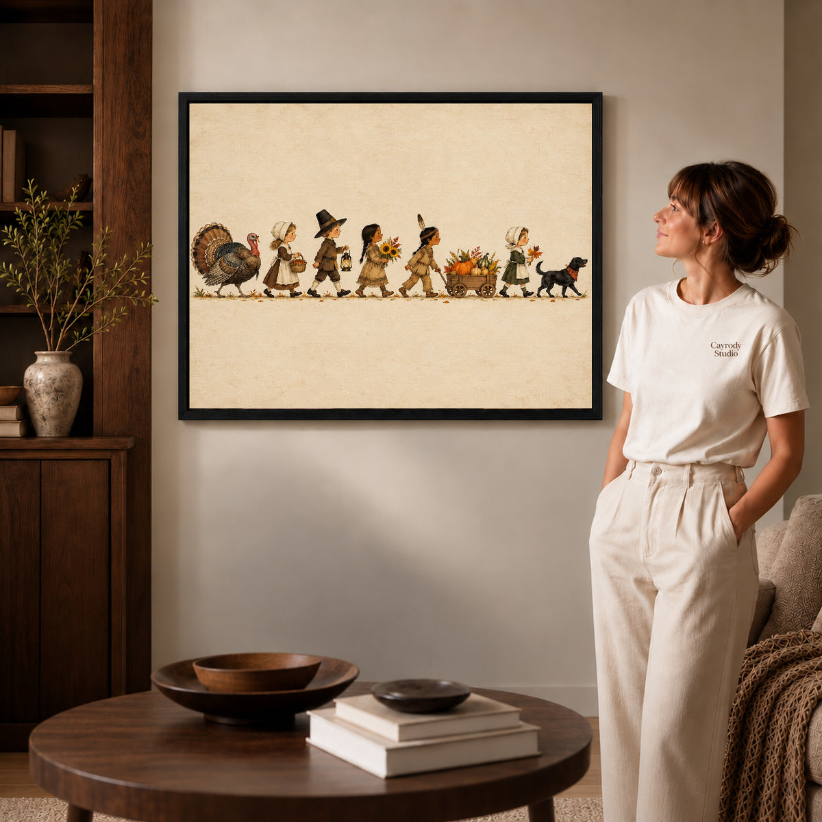 Harvest parade canvas art in a black frame above stacked books in a cozy living room.