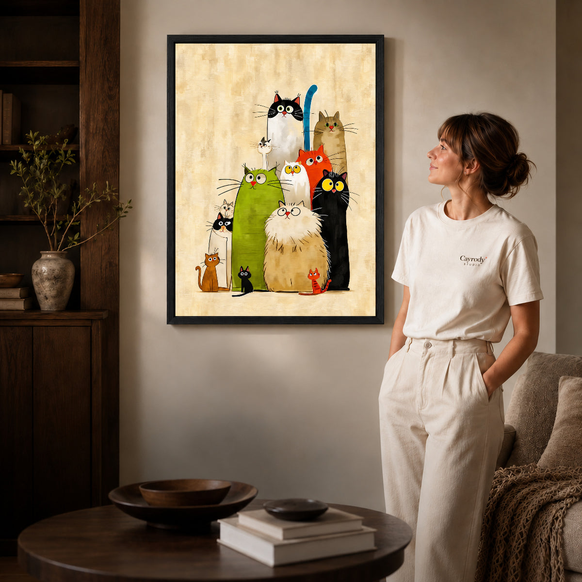 Colorful Cats canvas art in a black frame above books in a welcoming living room.