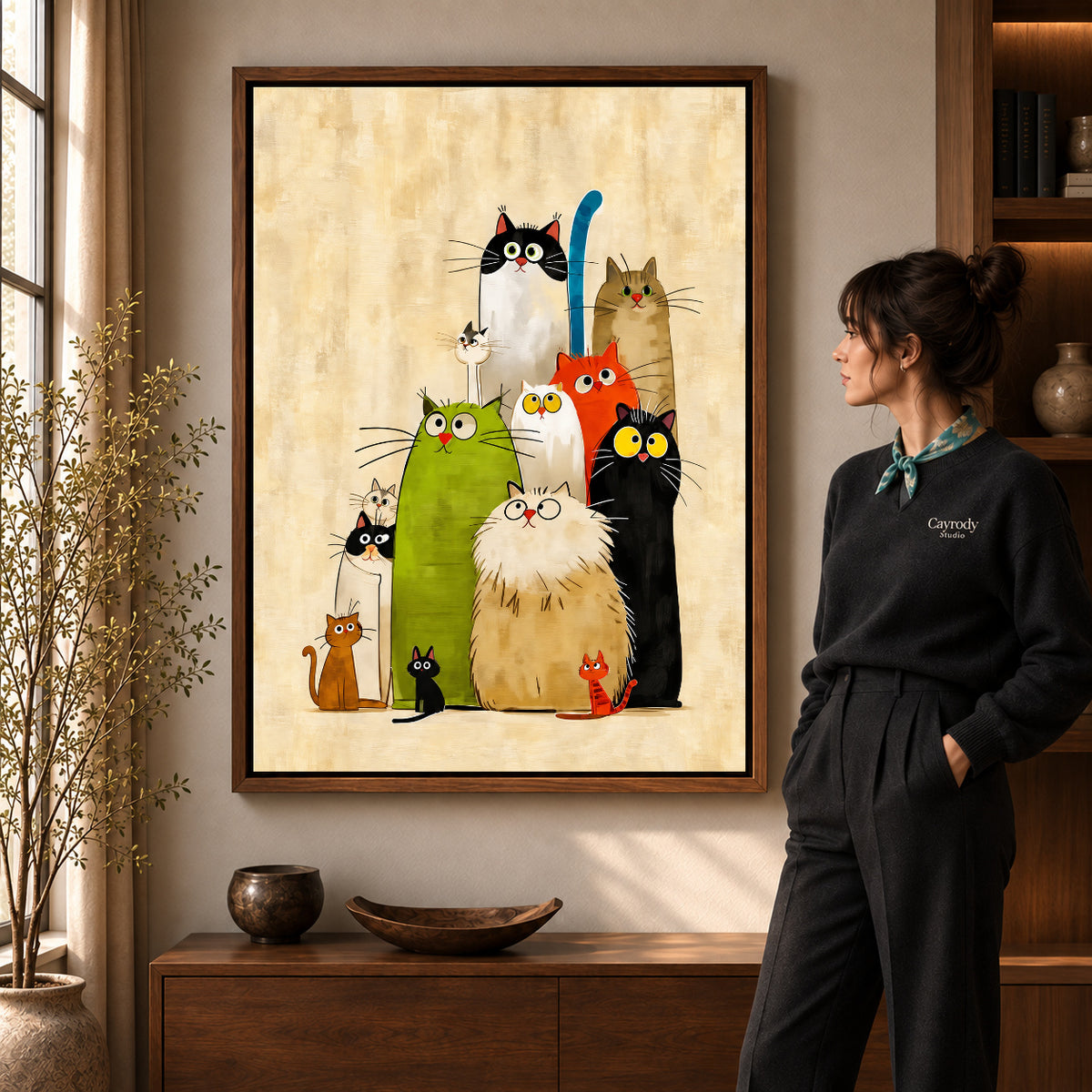 Walnut framed colorful cats canvas art shown beside a standing woman and a wooden console.