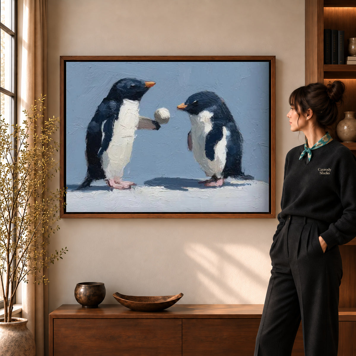 Penguin pair canvas art displayed in a walnut frame against a warm wall near a wooden console.