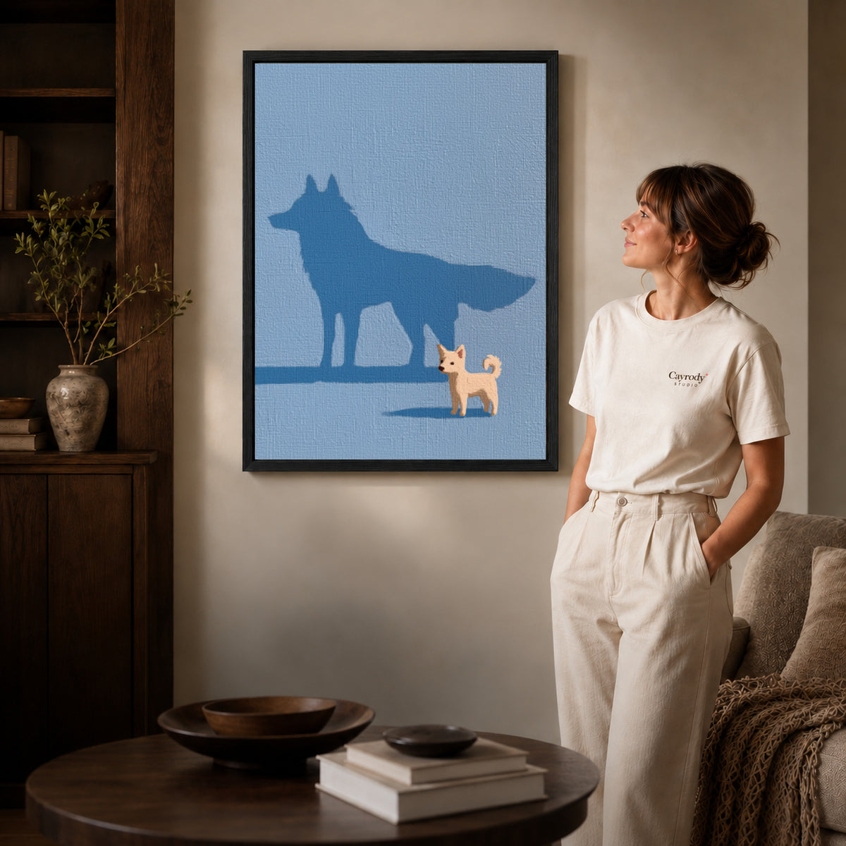 Puppy shadow canvas art displayed in a black frame beside a woman, with soft room lighting.