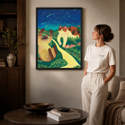 Starry cats canvas art in a black frame above stacked books in a cozy living room.