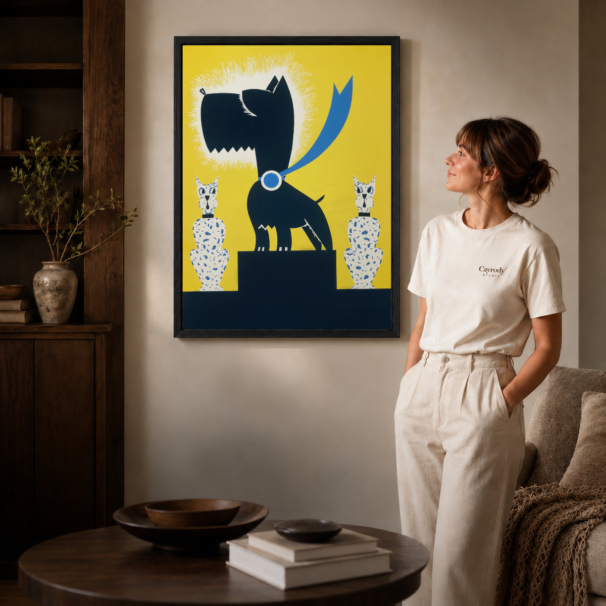 Black terrier canvas art displayed in a black frame beside a woman, with soft room lighting.