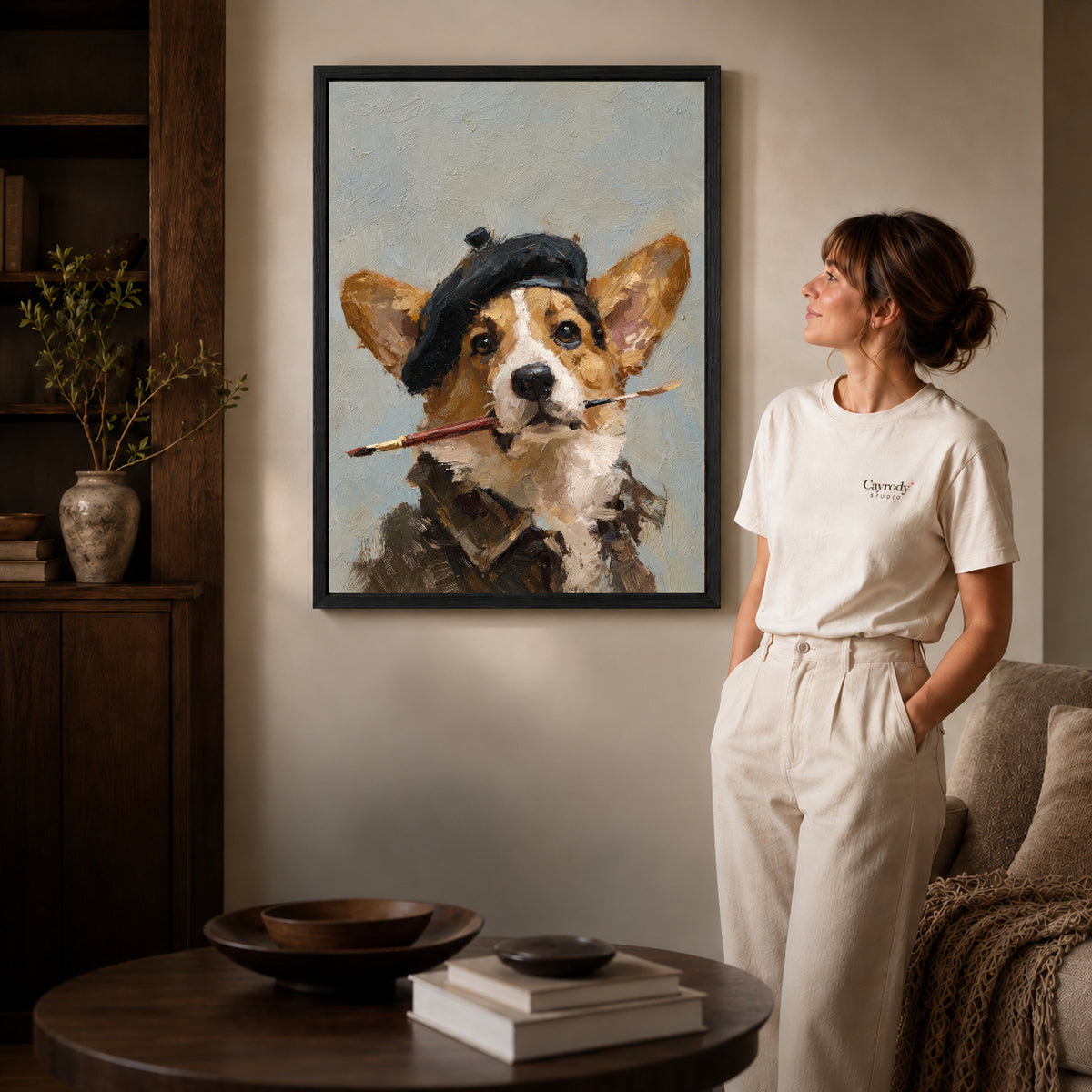 Artist corgi canvas art displayed in a black frame beside a woman, with soft room lighting.