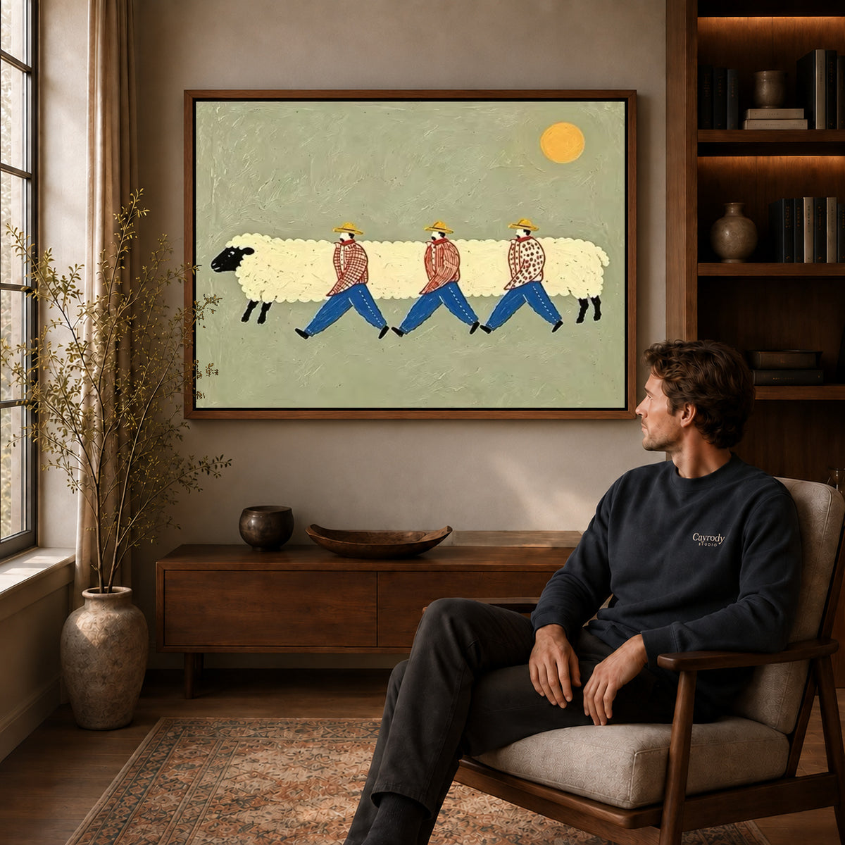 Sheep parade canvas art above a wooden console near a seated man and leafy branches.