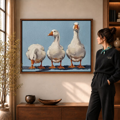 Three geese canvas art displayed in a walnut frame against a warm wall near a wooden console.
