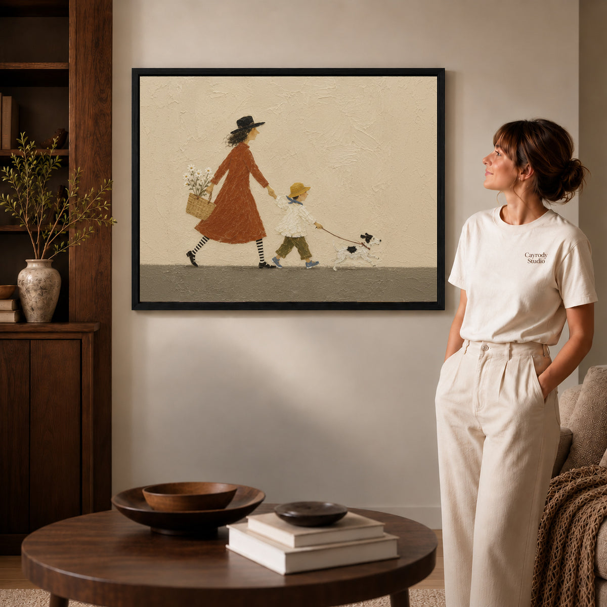 Family walk canvas art in a black frame above stacked books in a cozy living room.