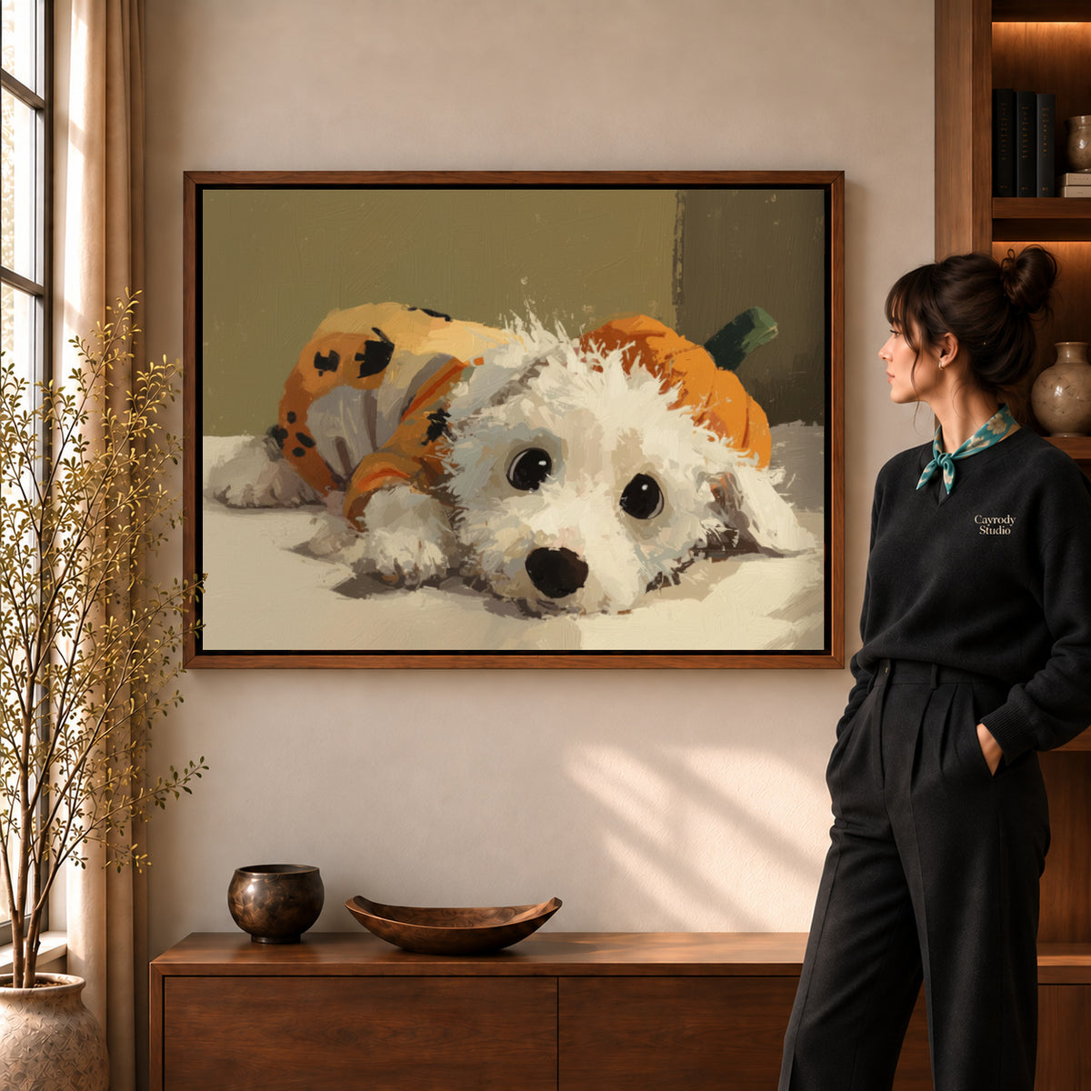 Pumpkin puppy canvas art in a walnut frame beside a woman in a warmly lit living room.