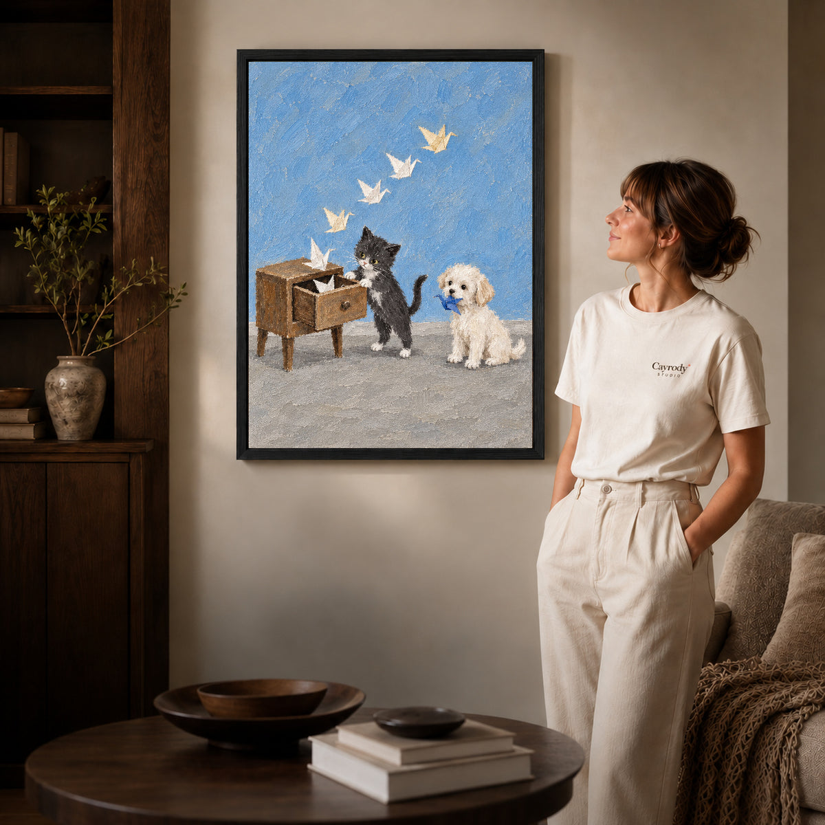 Paper Crane Pets canvas art in a black frame above books in a welcoming living room.