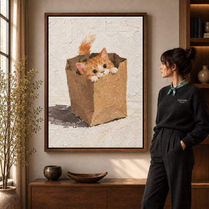 Paper bag kitten canvas art in a walnut frame beside a woman in a warmly lit living room.