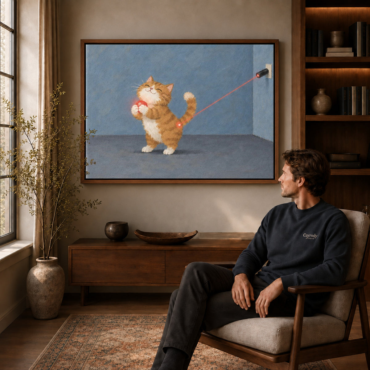 Ginger kitten canvas art above a wooden console near a seated man and leafy branches.