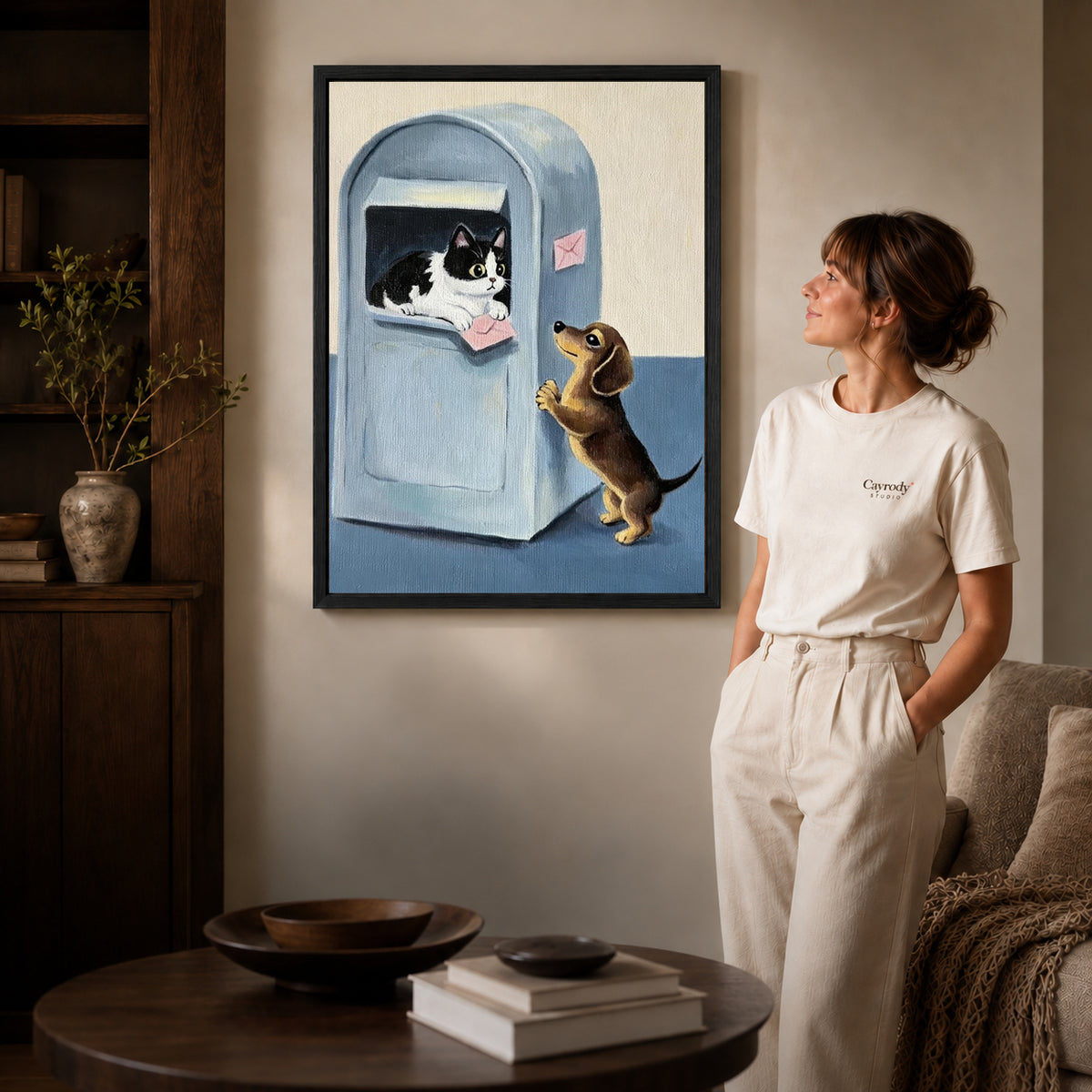 Mailbox companions canvas art displayed in a black frame beside a woman, with soft room lighting.